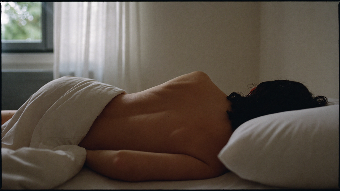 Personne dormant paisiblement dans une chambre lumineuse, allongée sur le côté au petit matin, lumière naturelle douce