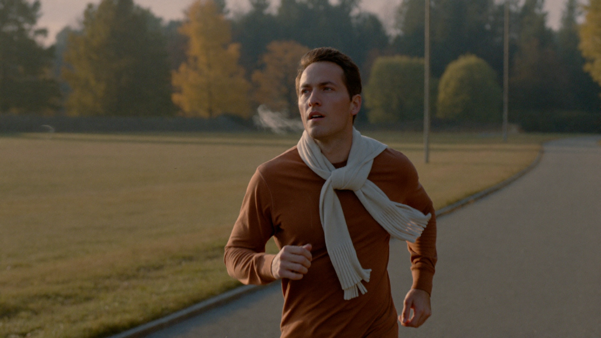 Coureur en jogging seul sur un chemin de parc par un matin frais d'automne, lumière naturelle douce